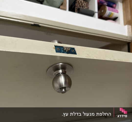 ידית דלת מתכתית עם מנעול על דלת עץ